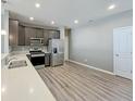 Well-lit kitchen with stainless steel appliances, gray cabinets, light countertops, and wood-look flooring at 673 Ballycastle Ct, Pendleton, IN 46064