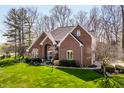 View of the home's red brick facade, large windows, manicured lawn, and walkway to the front door at 8845 Otter Cove Cir, Indianapolis, IN 46236