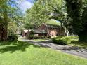 A two-story brick house with mature trees, a well-manicured lawn, and a long driveway at 925 Forest Dr, Anderson, IN 46011