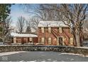 Traditional brick home with snow, a manicured lawn, and mature trees, offering classic charm and curb appeal at 925 Forest Dr, Anderson, IN 46011