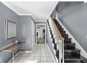 Inviting foyer features neutral walls, tiled flooring, and a staircase leading to the upper level, with a glimpse into the living area at 925 Forest Dr, Anderson, IN 46011