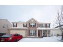 Charming two-story home with a brick facade, covered porch, and attached two-car garage on a snowy winter day at 1136 Meriman Dr, Greenwood, IN 46143