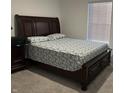 Cozy bedroom featuring a large wooden bed frame with a patterned comforter, complemented by a matching nightstand and window blinds at 10317 Caprock Canyon Dr, Indianapolis, IN 46229