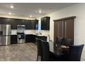 Modern kitchen featuring dark cabinets, stainless steel appliances, and an adjacent dining area with a sleek, black table and seating for six at 10317 Caprock Canyon Dr, Indianapolis, IN 46229