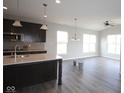 Open concept kitchen boasts an island, dark cabinetry, stainless steel appliances, and hardwood flooring at 10502 Oak Bend Blvd, Indianapolis, IN 46239