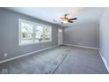 Spacious living room featuring new gray carpet, gray walls, a ceiling fan, and large window at 1235 Indiana Ave, Anderson, IN 46012