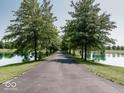 Long driveway through a tree lined landscape with a pond on either side provides a peaceful entrance at 12484 E 156Th St, Noblesville, IN 46060
