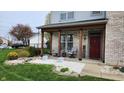 Inviting covered front porch with seating area, a red front door and decorative landscaping at 1501 Willshire Dr, Greenwood, IN 46143
