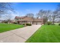 Side view of a two-story brick home featuring a three-car garage and lush green lawn at 7018 W Anton Way, New Palestine, IN 46163