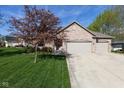 Charming brick home with a three-car garage and a beautifully landscaped front yard and mature tree at 11 Stratford Way, Danville, IN 46122