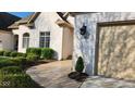 Classic white brick home featuring a beige garage door, lush landscaping, and refined outdoor lighting at 1655 Rosebud Ln, Greenwood, IN 46143