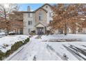 Charming multi-story condo with a striking blue door, complemented by a neatly landscaped yard covered in a blanket of snow at 240 Legends Creek Pl # Apt 205, Indianapolis, IN 46229