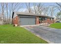 Side angle of brick home showing attached garage, asphalt drive and well maintained front yard at 3549 Woodale Rd, Indianapolis, IN 46234