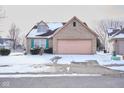 A well-maintained home with a brick facade and a two-car garage sits on a snow-dusted lot at 4912 Eagle Talon Ct, Indianapolis, IN 46254