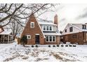 A view of the brick home with detailed architecture and a snow-covered yard at 5715 N Delaware St, Indianapolis, IN 46220