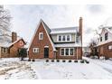 Beautiful brick home with snow-covered yard, mature trees, and architectural details at 5715 N Delaware St, Indianapolis, IN 46220