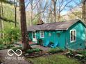 A cozy turquoise cottage sits among mature trees and landscaping, offering a serene and private setting at 7166 N Oak Ridge Rd, Morgantown, IN 46160