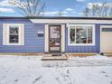 A bright, blue one-story home with white trim and a metal roof, situated on a snow-covered lot at 930 Edgewood Dr, Mooresville, IN 46158