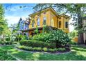 Beautiful yellow home with well-manicured lawn and lush greenery at 1409 N Park Ave, Indianapolis, IN 46202