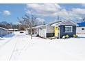 Charming single-story home featuring a yellow door, gray facade, and well-maintained landscaping, covered in snow at 180 N Indiana St, Mooresville, IN 46158