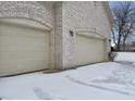 Attached garages with an arched brick entryway on a snow-covered driveway and yard at 5791 Station Hill Dr, Avon, IN 46123