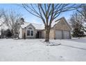 Charming stone-faced home with a two-car garage and a snow-covered lawn at 6751 Wild Cherry Dr, Fishers, IN 46038