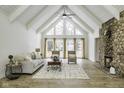 Living room with vaulted ceiling, many windows, stone fireplace, and hardwood flooring at 810 N Cherry Wood Ln, Muncie, IN 47304