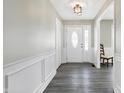 Well-lit foyer with wood-look floors, wainscoting detail, a decorative light fixture, and a front door with sidelights at 935 Elmwood Cir, Noblesville, IN 46062