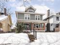 Attractive home with a classic design, featuring a inviting front porch and a snow-covered yard, creating curb appeal at 102 N Bosart Ave, Indianapolis, IN 46201