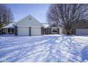 Inviting home featuring a two-car garage, brick accents, and snowy front yard at 10953 Mount Vernon N Trl, Indianapolis, IN 46229