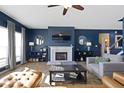 Cozy living room with blue walls, a fireplace, a ceiling fan, and plenty of natural light at 12773 Broncos Dr, Fishers, IN 46037