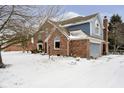 Angle view of the house with an attached two-car garage and snow covered yard at 13895 Silver Stream Dr, Carmel, IN 46032