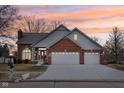 Charming brick home with gray siding, three-car garage, and a well-maintained front yard at sunset at 3226 Raylin Dr, Indianapolis, IN 46227