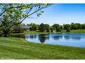 Scenic view of a tranquil pond surrounded by lush green grass and mature trees in a residential area at 6034 Bluecrest Dr, Brownsburg, IN 46234