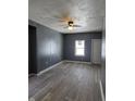 An open living room featuring newly installed flooring, a ceiling fan, and a bright window at 724 E Beecher St, Indianapolis, IN 46203