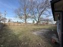 Large fenced backyard, a concrete patio, and mature trees provide privacy in a quiet residential neighborhood at 806 Country Ln, Anderson, IN 46013
