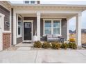 Inviting covered front porch with seating area, decorative plants, and ample natural light at 8660 Hudson Way, Brownsburg, IN 46112