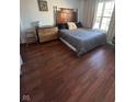 Bedroom with hardwood floors and a bed with a wooden headboard next to a dresser at 1013 Redwood Dr, Lebanon, IN 46052