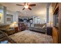 Open concept living room with hardwood floors, ceiling fan, adjacent kitchen and dining area, and comfortable seating at 12991 Pennington Rd, Fishers, IN 46037