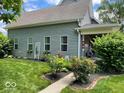 Landscaped home exterior with lush green lawn, colorful flowerbeds, and well-maintained gray siding at 1390 Greenfield Ave, Noblesville, IN 46060