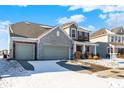 Lovely two-story home with a gray stone and brick exterior, a two-car garage, and a driveway with some snow at 5648 Juniper Ct, Whitestown, IN 46075