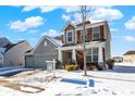 Beautiful home with a mix of stone and brick, a two-car garage, and a partially snow-covered front yard at 5648 Juniper Ct, Whitestown, IN 46075