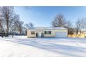 Charming yellow home with a snow-covered front yard and attached garage at 5757 E 21St St, Indianapolis, IN 46218