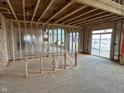 Under-construction living room highlighting the wood framing and silver insulation, with a sliding glass door leading to outdoor space at 618 Firefly Ct, Greenfield, IN 46140