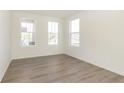 Bright bedroom featuring pristine white walls, wood-look flooring, and three large sunny windows at 7197 Barrett Dr, Brownsburg, IN 46112