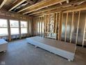 Unfinished living room displaying exposed framing, insulation, and windows, with drywall and plywood on the floor at 750 Oakleaf Dr, Greenfield, IN 46140
