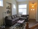 Inviting living room with hardwood floors, a large couch, and a bright, multi-paned window at 8148 Shores Edge Way, Indianapolis, IN 46237