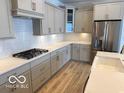 Well-lit kitchen featuring sleek, stainless steel appliances, gray cabinets, and stylish white countertops at 9124 Bryce Cir, Zionsville, IN 46077