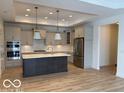 Modern kitchen with a center island, stainless steel appliances, stylish pendant lights, and hardwood flooring at 9124 Bryce Cir, Zionsville, IN 46077