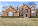 Stately brick home showcasing architectural details and a well-maintained lawn in a serene setting at 14085 Honey Tree Dr, Carmel, IN 46032